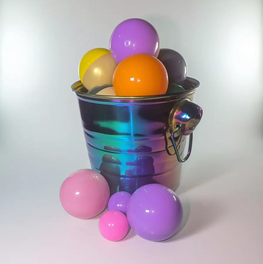 A rainbow-iridescent bucket overflows with colorful jewelry capsules balls.